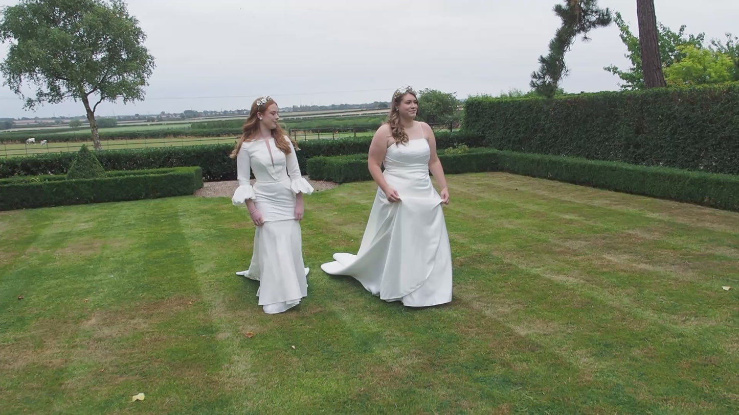 Two beautiful brides walking through a lawned garden wearing the Howard and Gilded Garden Tiaras